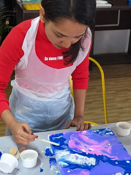 A participant focused on her pour painting, carefully guiding the flow of the colors.