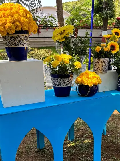 A detail shot from the "Jaipuri Blue Pottery" themed event, with yellow marigolds arranged in a blue and white ceramic pot on a matching table.