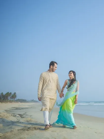 A romantic stroll on a Goan beach. The couple's colorful outfits pop against the blue sky and sea, making for a vibrant and beautiful pre-wedding picture.