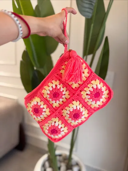 A styled shot of our pink granny square pouch. The tassel adds a fun, bohemian touch.