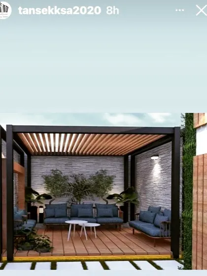 A compact and stylish pergola with a metal frame and a wooden slat roof. The design includes a stone-textured back wall and is furnished with modern blue sofas, perfect for a small patio.