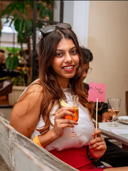 A guest enjoying a cocktail and holding a "Roxie Loves You" sign. This captures the fun, personal, and welcoming spirit I cultivate at all my events.
