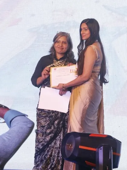 A student receives her award certificate on stage, a proud moment recognizing her design achievements.