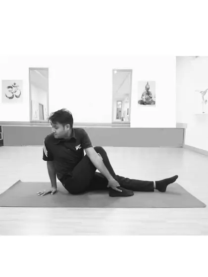 Ardha Matsyendrasana (Half Lord of the Fishes Pose) is a classic seated spinal twist. This pose energizes the spine, stimulates digestion, and helps to detoxify the internal organs, shown here in a clean studio setting.