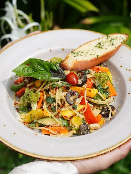 A healthy and flavorful aglio e olio pasta, tossed with fresh vegetables, olives, and herbs.