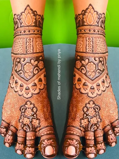 A beautifully stained, full-coverage foot mehendi with traditional floral and geometric patterns.