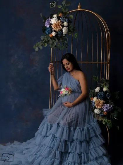 A moment of quiet reflection. Seated in the golden cage, this mama-to-be looks down at her bump with love, surrounded by dreamy pastel florals.