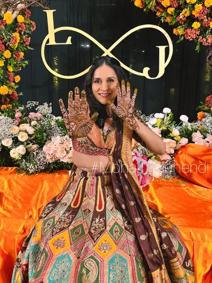 An elegant client posing at her beautiful mehndi event. Her graceful design complements her stunning lehenga perfectly. It's a joy to be part of such grand celebrations.