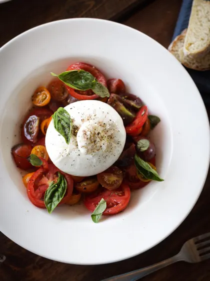 A beautiful Burrata and heirloom tomato salad, showcasing the importance of fresh, high-quality ingredients and elegant plating.
