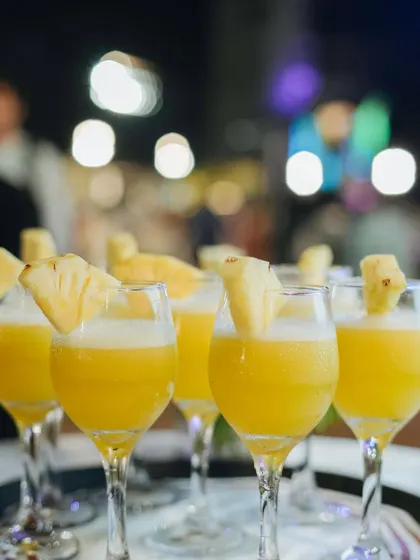 A tray of refreshing pineapple mocktails, perfect for a tropical-themed or summer event. The bokeh background highlights the celebratory atmosphere we help create.
