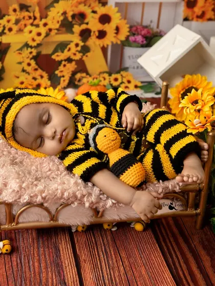 Our little bumblebee taking a nap on a tiny bed, surrounded by sunflowers and holding a matching bee toy.