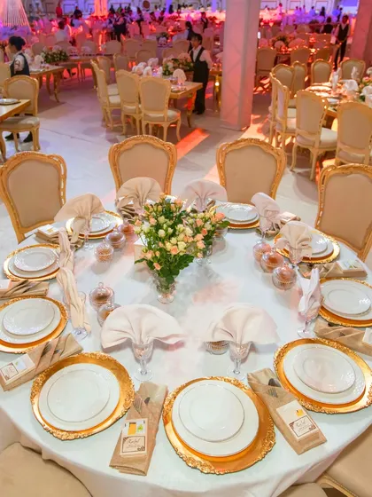 Step into luxury with this breathtaking wedding reception setup. The elegant round tables feature gold-rimmed plates, sophisticated centerpieces, and perfectly folded napkins, reflecting style and class.