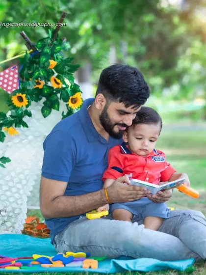 "Story time with Dad." A father reads a book to his son in front of a teepee tent during their outdoor photoshoot. These are the quiet, bonding moments that matter most.