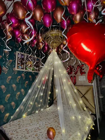 Another view of the romantic room setup, showing the 'I LOVE YOU' foil balloons and the dense arrangement of heart-shaped balloons on the ceiling.