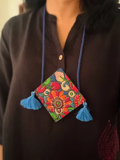 A vibrant, kite-shaped pendant with a hand-painted floral design inspired by Madhubani art. The playful tassels add a touch of boho charm.