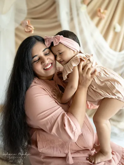 A mother gives her daughter a big, happy hug. Their closed eyes and joyful smiles show the deep love and comfort they find in each other.