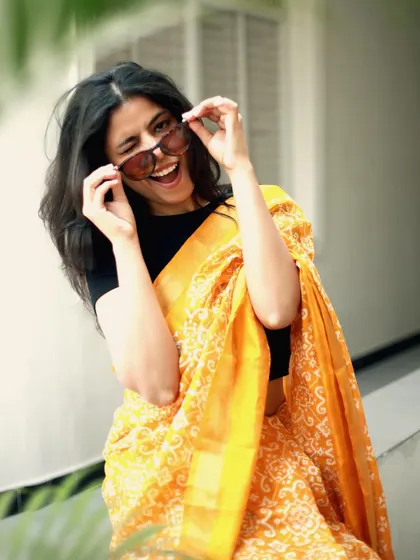 A playful and candid moment, adding personality to this yellow saree shoot, making the content more engaging and relatable.