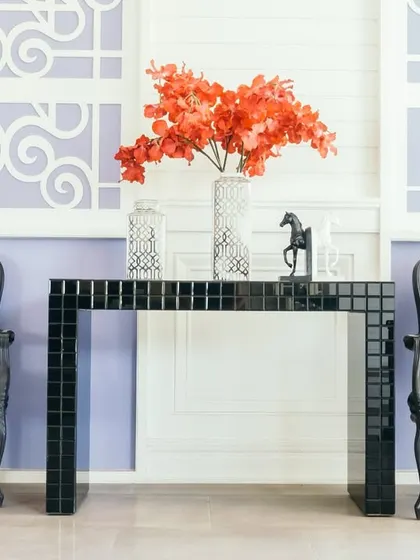 A dramatic and elegant entryway or seating nook, combining vintage-style striped chairs with a modern, glossy black console table against a patterned wall for a classic yet bold statement.