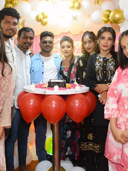A group of friends and family posing for a photo at a birthday party.