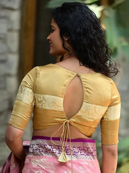 A golden blouse with a keyhole back and tie-up tassel. The sleeves feature a contrasting brocade panel.