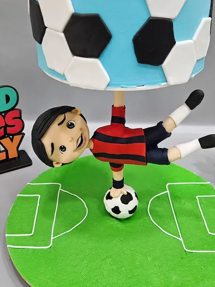A close-up of the upside-down footballer figurine, balancing the entire structure on a soccer ball. The details are key to making the illusion work.