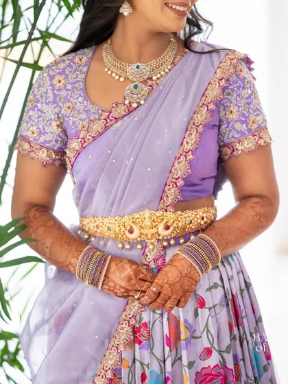 A mid-shot of the Langa Dhavani, showing the embroidered blouse, the traditional gold belt (Vaddanam), and the floral skirt.