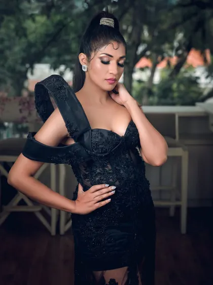 A full-length shot of actress Iti Acharya in an elegant black gown. This photo highlights the dress's unique design and is suitable for fashion features or red carpet-style portfolios.