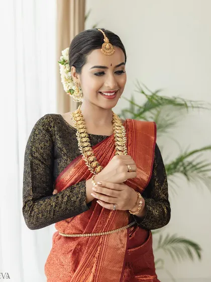 A happy and radiant portrait of the model, showcasing her smile and the beautiful antique gold jewellery. The natural setting with a plant in the background adds a fresh touch.