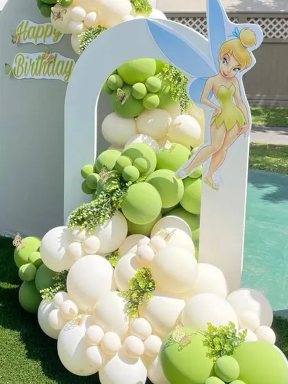 A magical Tinkerbell party set in a green backyard. The balloon arrangement flows out of a white arch, perfectly complementing the natural surroundings.