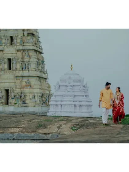 A couple walks hand-in-hand near a temple, dressed in colorful traditional clothing. This shot captures the journey they are beginning together.