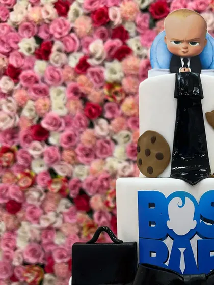 This close-up of a three-tiered Boss Baby cake highlights the detailed fondant work, from the tiny cookies to the formal suit design, making it a truly impressive celebration cake.