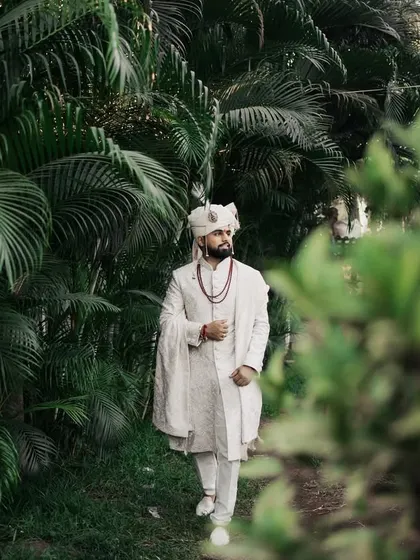 The groom takes a stroll through a path surrounded by greenery, captured in a candid, natural style.