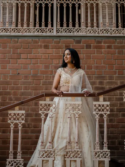 The bride posing against a brick wall, her elegant white engagement outfit shining in the natural light.