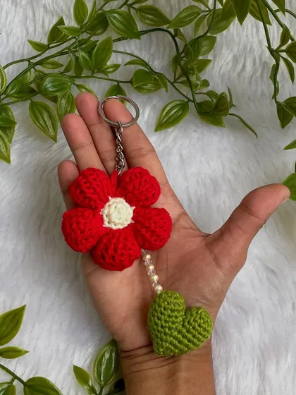 A pretty red flower keychain made with a special Tunisian crochet technique. The little green heart and pearl details make it extra special.