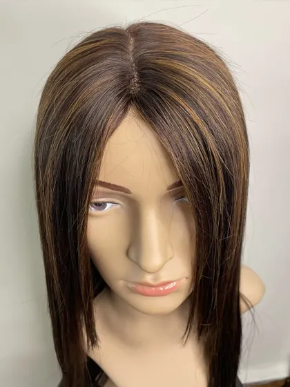 A close-up of a highlighted silk wig on a mannequin. The silk base provides a flawless, natural-looking scalp that enhances the realism of the piece.