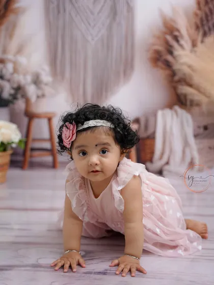 A sweet crawling pose in a delicate pink dress, this shot captures the innocence and charm of a baby girl during her first birthday session.