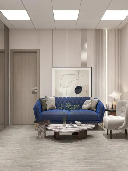 A lounge area in a modern office, featuring a stylish blue tufted sofa and minimalist decor. The space is designed for comfort and relaxation.