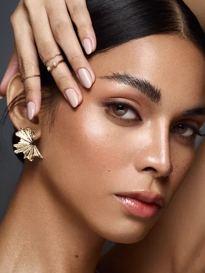 The essence of clean beauty. This shot celebrates natural, glowing skin, brushed-up brows, and minimal styling with a delicate gold earring.