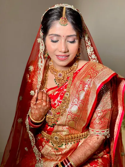 A close-up of a beautiful South Indian bride. The makeup is kept classic and radiant to complement her traditional red and gold silk saree.