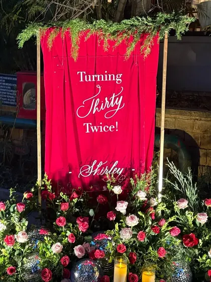 My signage is often the first thing guests see, setting the tone for an event. I loved designing this minimal yet dramatic acrylic sign for a 60th birthday, where my calligraphy popped against the rich red backdrop, disco balls, and lush florals.