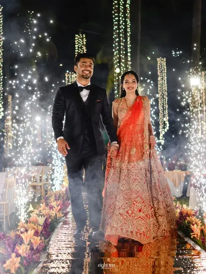The couple's grand reception entrance through an aisle of sparklers. The path is lined with flowers and fairy lights, leading them into a night of celebration.
