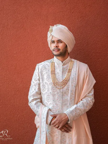 A classic groom portrait against a simple, textured background, highlighting his attire.