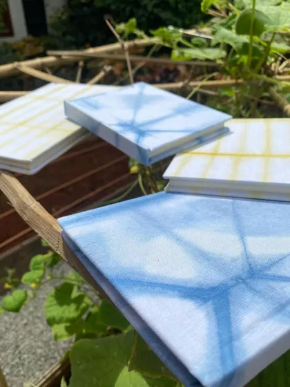 The tie-dyed notebooks captured in a natural setting. The covers, wrapped in hand-dyed fabric, reflect the beauty of the nature that inspired them.