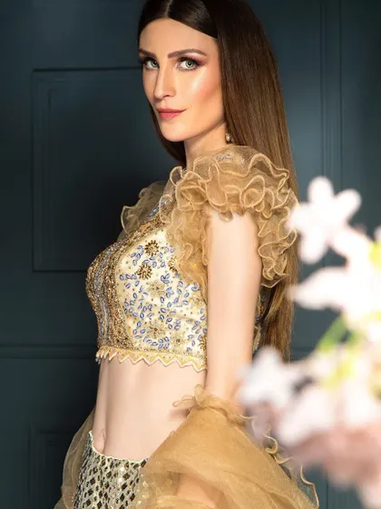 A mid-shot of the model in a golden lehenga, focusing on the detailed blouse and her confident gaze. This type of portrait is great for showcasing both the outfit and the model's presence.