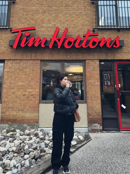 A classic college life moment: grabbing a coffee at Tim Hortons in a cozy puffer jacket.