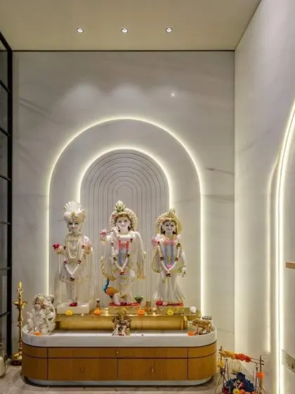We create tranquil sacred spaces that blend modern design with traditional reverence. This pooja room features elegant white marble walls with arched, back-lit panels that create a serene glow. The custom wooden base provides a warm, natural element, resulting in a peaceful corner for prayer and reflection.