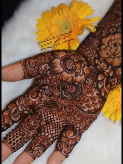A macro shot of the intricate floral work on the palm, set against a bright yellow flower.