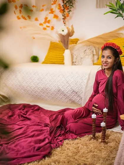 A peaceful maternity portrait in our cozy boho setup. The client is seated comfortably in a deep red gown, creating a warm and intimate atmosphere for her solo shoot.