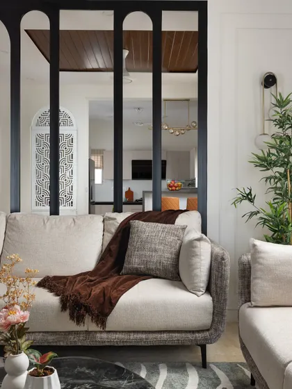 A view from the living room sofa, looking past the arched metal partition towards the dining area and kitchen. This design choice maintains an open feel while creating distinct functional zones.