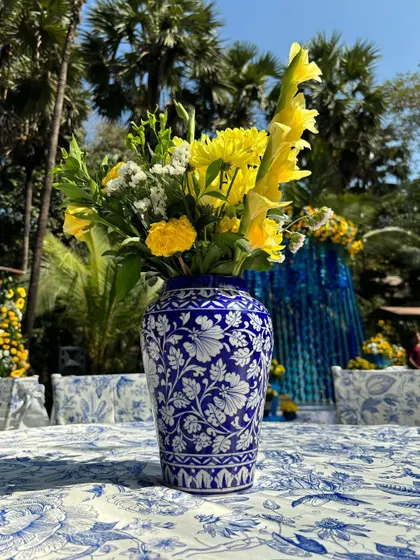 A close-up of a centerpiece from the "Jaipuri Blue Pottery" theme, with a beautiful patterned vase and yellow flowers.